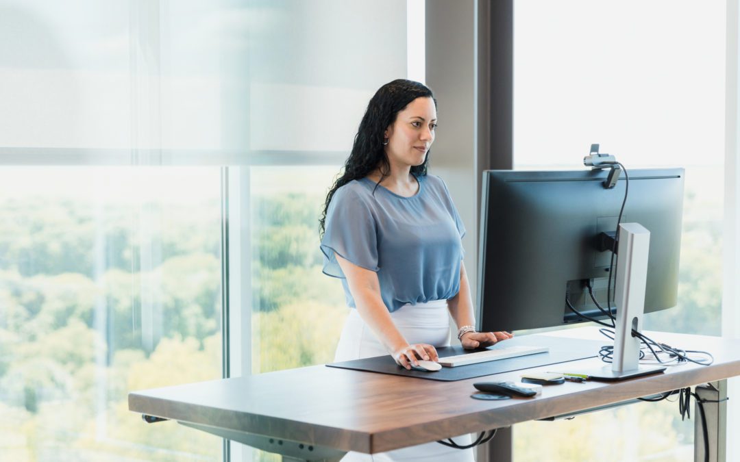 Using standing desk, female CEO works in corner office